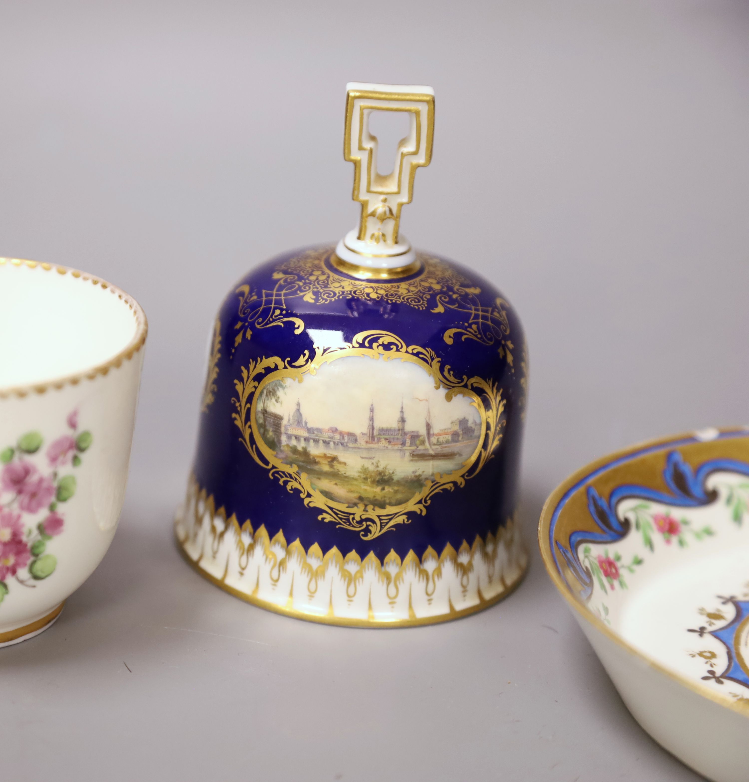 A Meissen hand-painted table bell, a Vienna saucer, diameter 13.5cm, and a Sevres cup